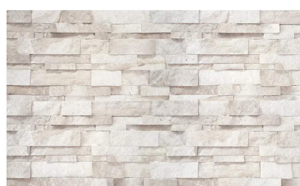 A wall of cream stone laid as a random-split ledger panel, courses stacked in staggered relief.