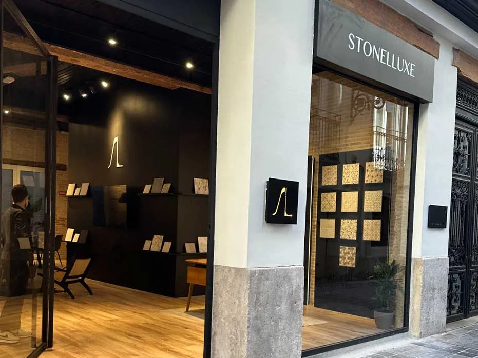 The Valencia shopfront at street level: the Stonelluxe sign over a glass door, tile samples on dark shelves inside.