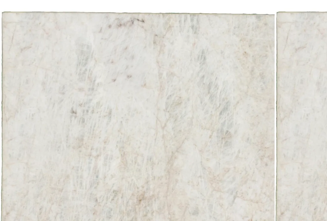 A close, raking view across a pale slab: fine crystalline veining and translucent depth, the sawn edge just visible at the top.